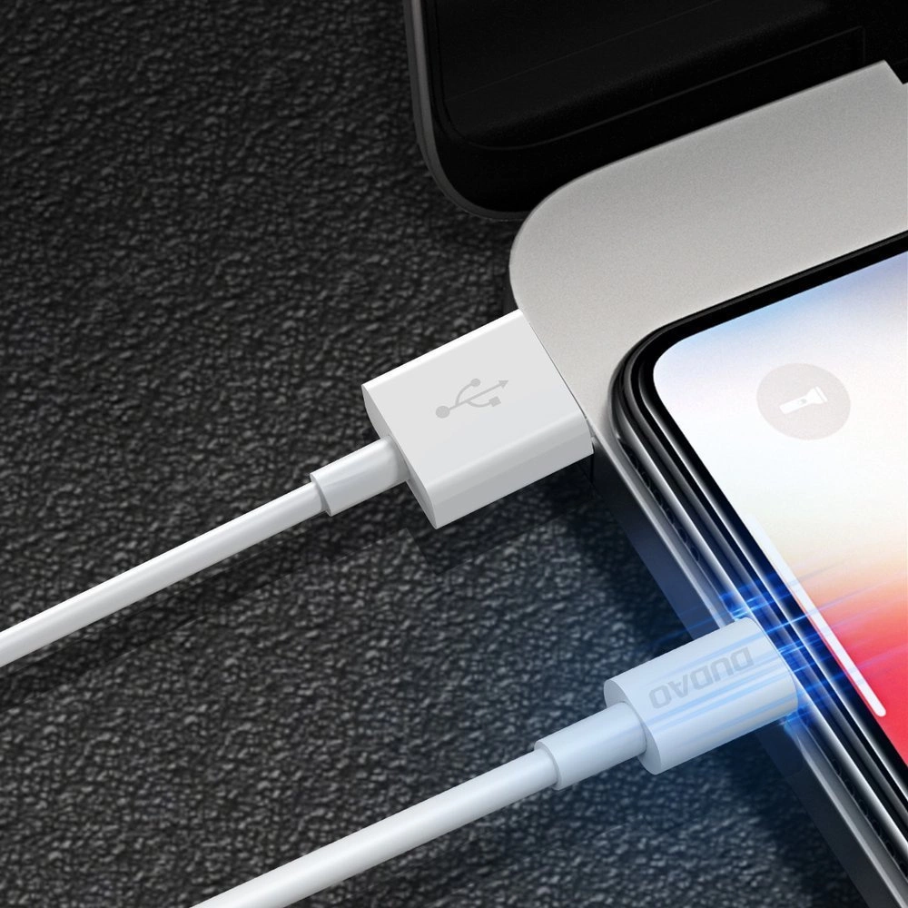 Un cavo USB bianco è collegato a uno smartphone, in carica su una superficie scura.