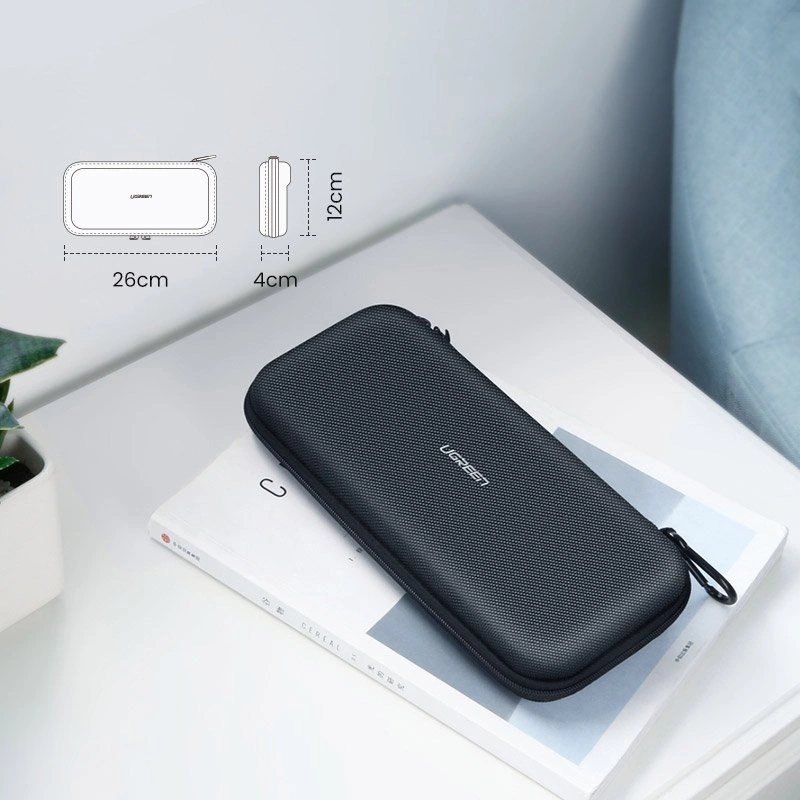 Custodia nera UGREEN con zip, 26x12x4cm, appoggiata su un libro.