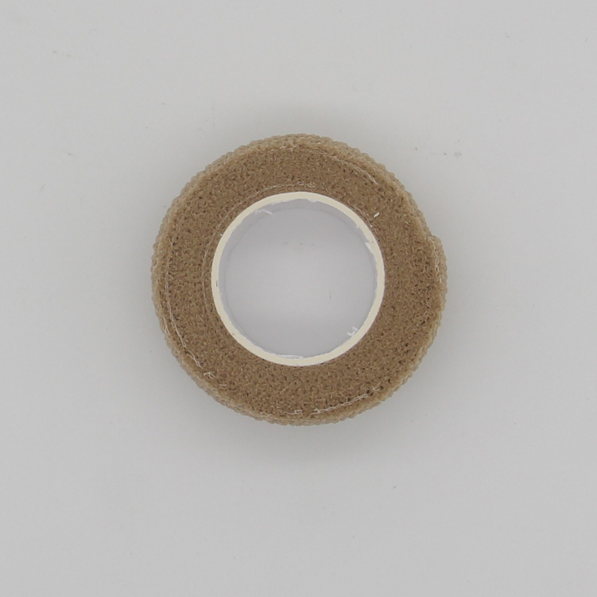 Un rotolo di nastro elastico coesivo color tortora su sfondo grigio.