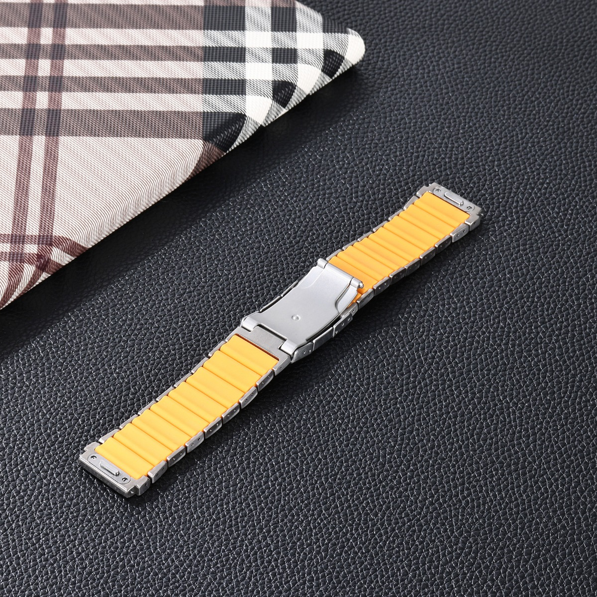 Ein gelbes Uhrenarmband mit silbernem Verschluss auf schwarzem Hintergrund.