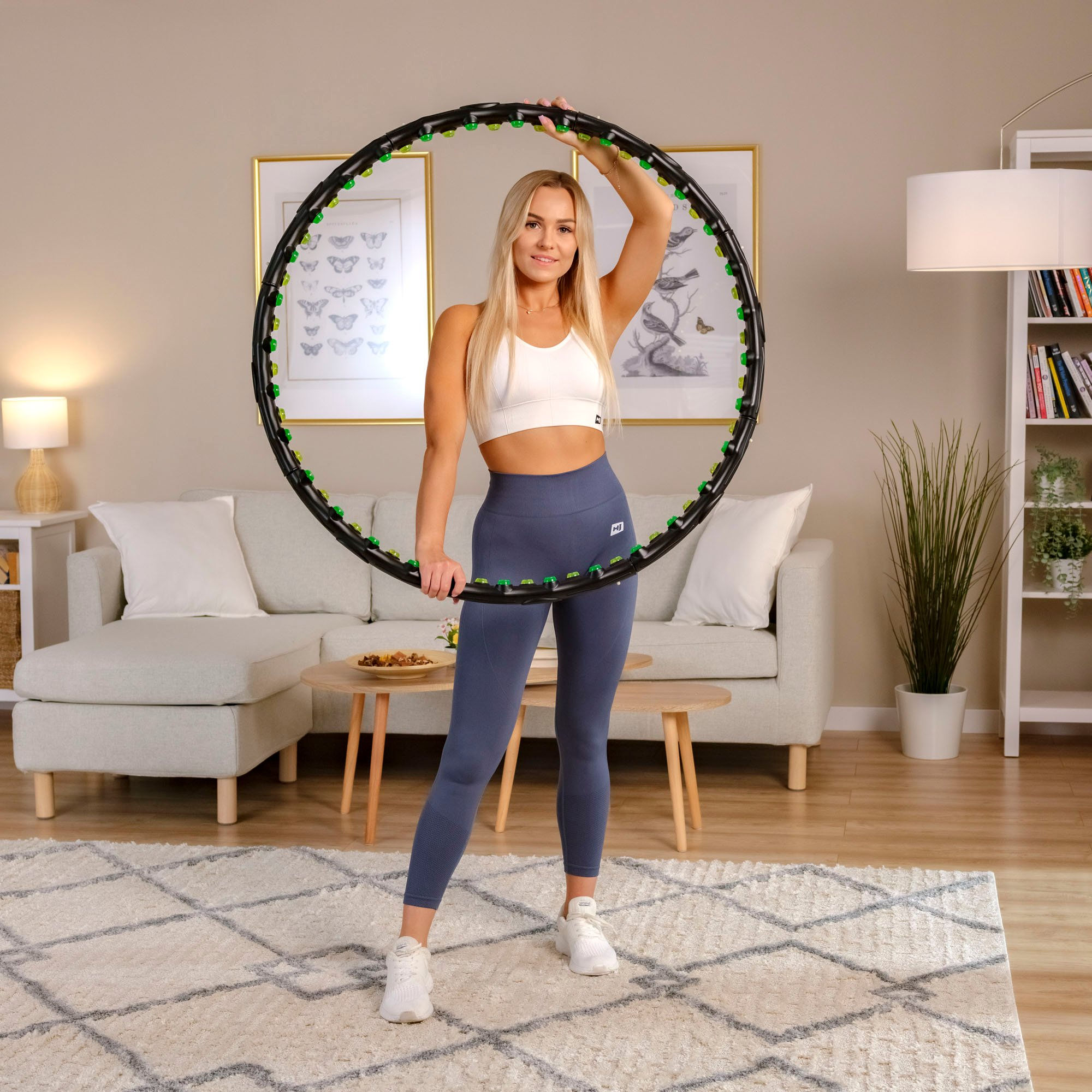 Eine Frau mit langen blonden Haaren hält einen Hula-Hoop-Reifen mit grünen Akzenten.