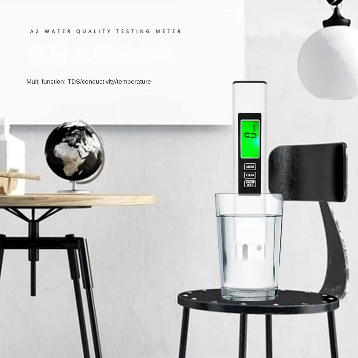 Ein weißer Wasserqualitätsprüfer mit grünem Bildschirm in einem Glas Wasser.