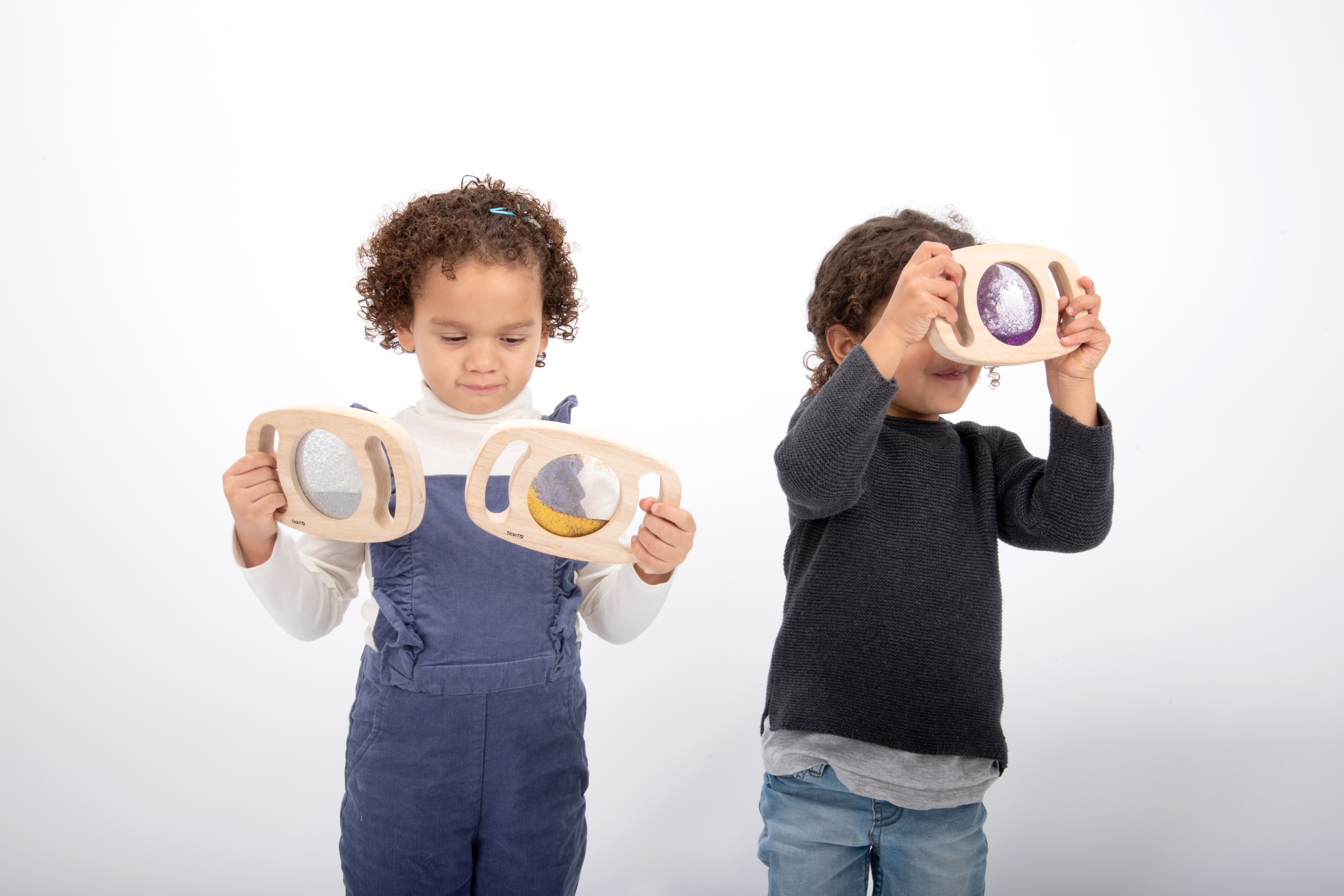 Dos niños juegan con juguetes de marco de madera con brillantina y arena.