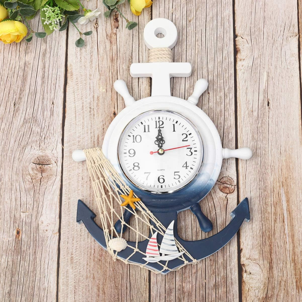 Eine maritime Ankeruhr mit Steuerrad und Segelbooten, Muscheln und Seestern.