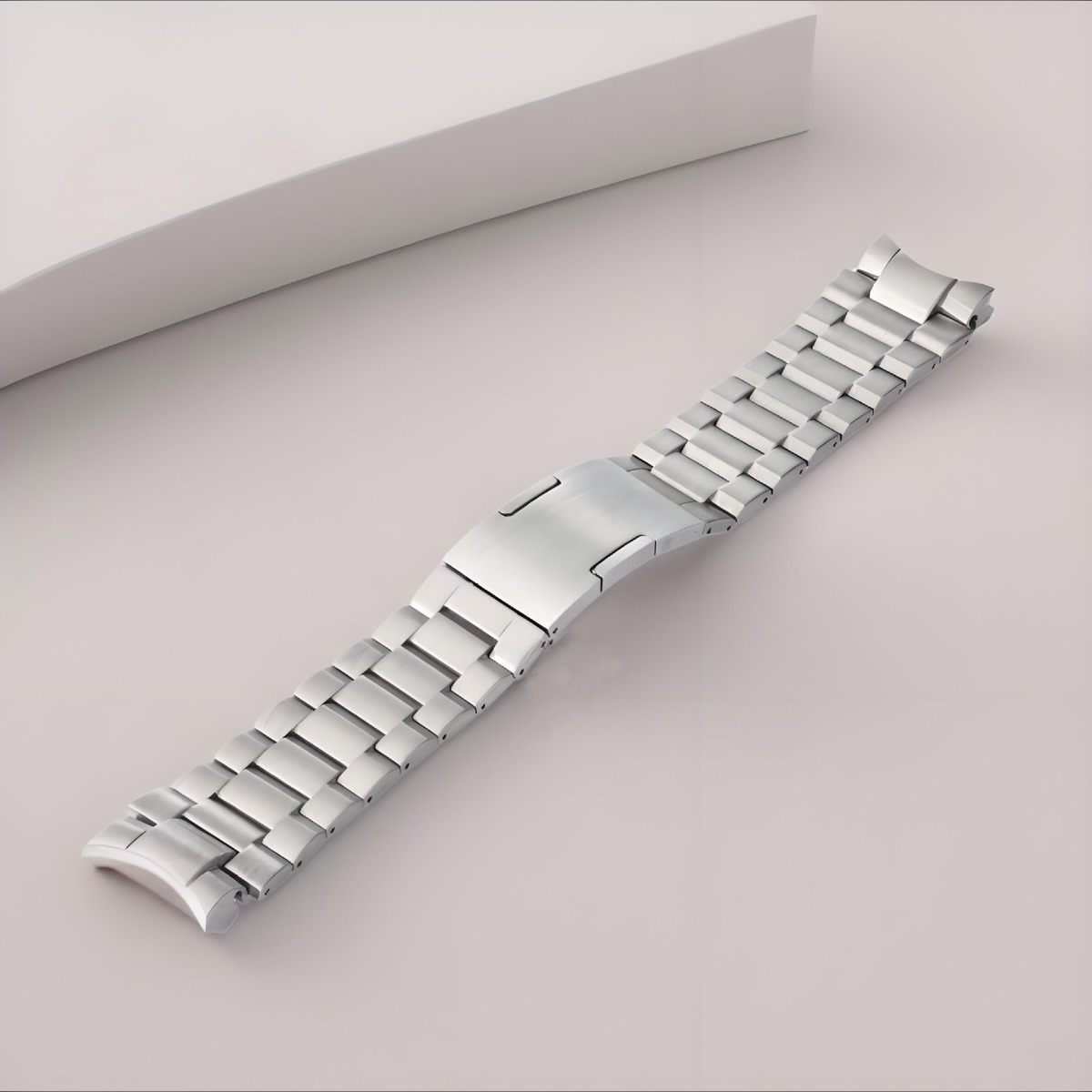 Ein silbernes Metallarmband mit Faltschließe liegt auf einem hellen Untergrund.