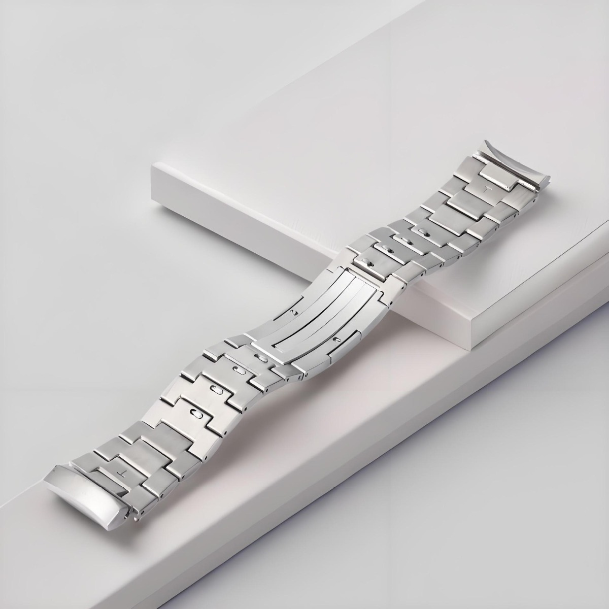 Ein silbernes Metallarmband liegt auf weißen Podesten.