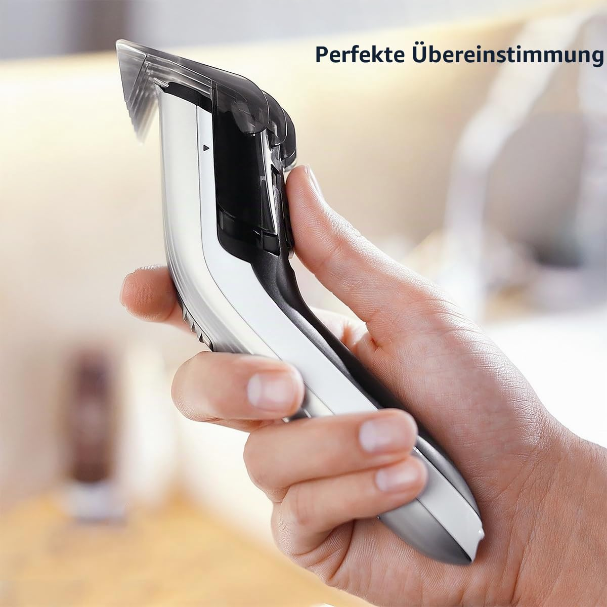 Eine Hand hält einen silbernen und schwarzen Haartrimmer mit angebrachten Aufsätzen.
