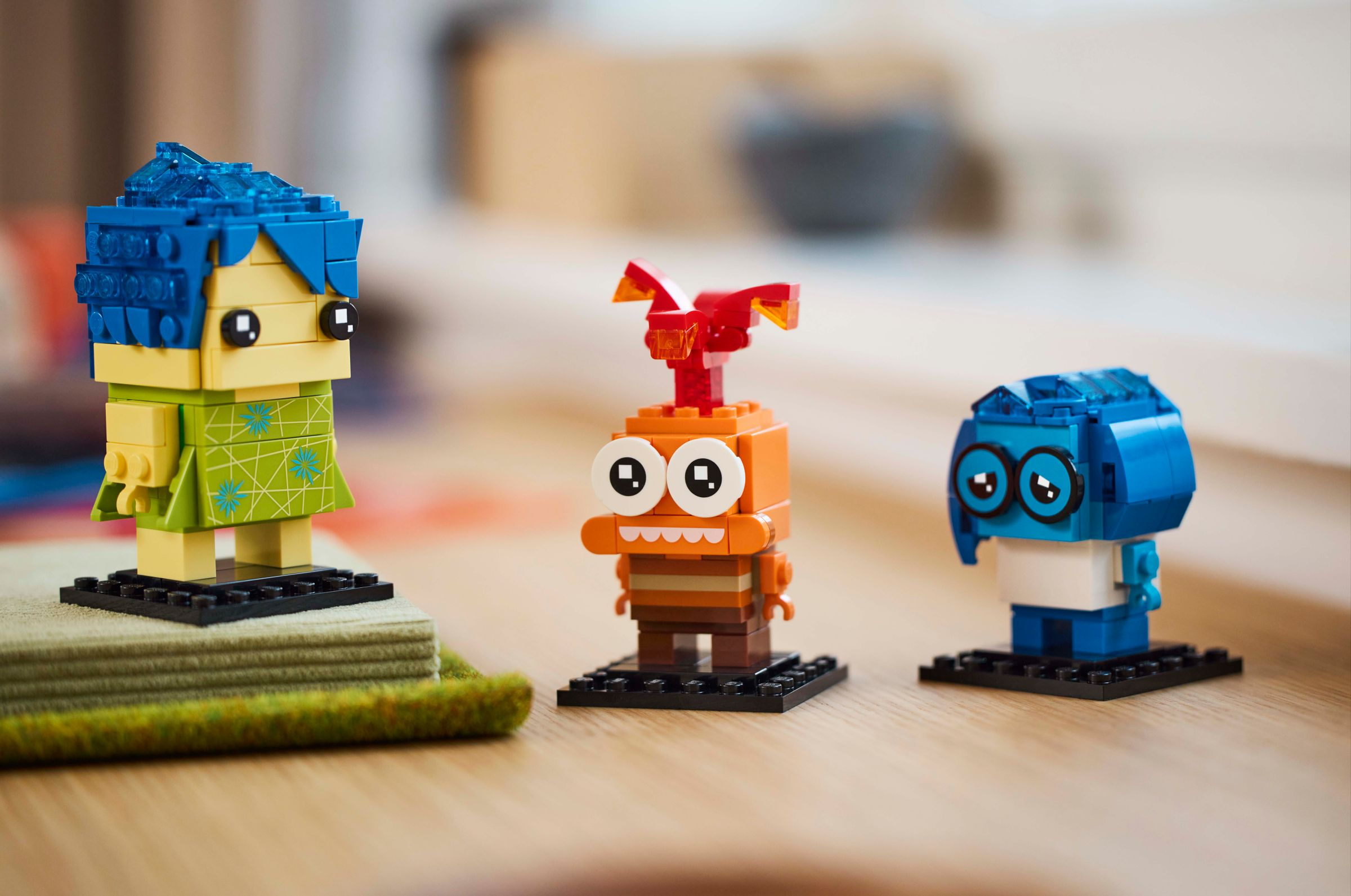Drei Lego-Figuren: eine gelbe mit blauer Frisur, eine orangefarbene und eine blaue.
