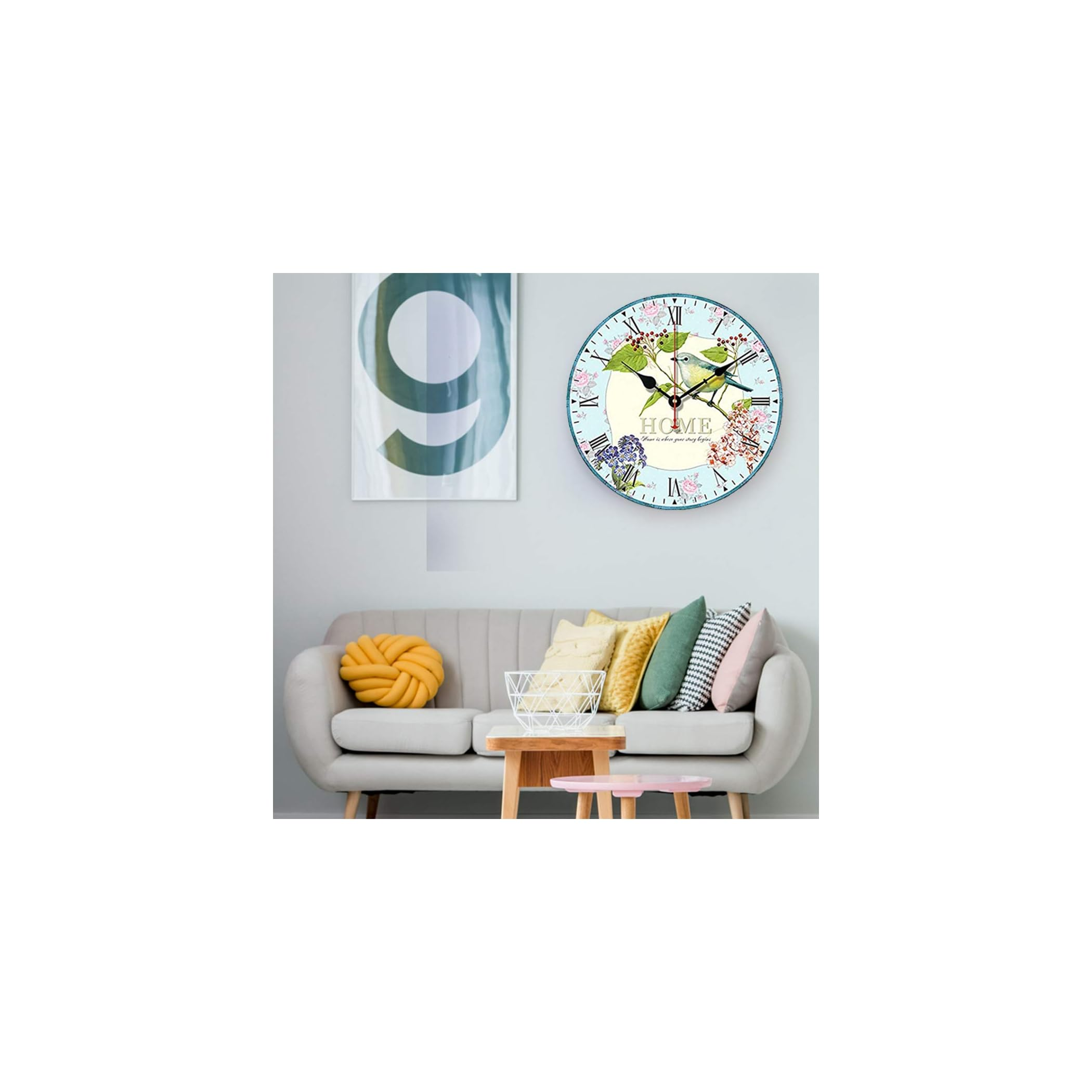 Eine runde Wanduhr mit Vogel- und Blumenmotiv hängt über einem Sofa.