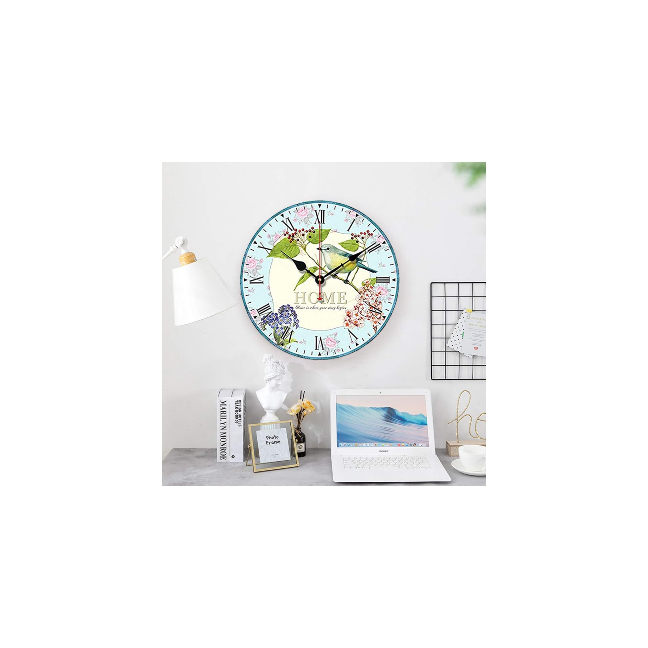 Eine Wanduhr mit Vögeln und Blumen, daneben ein Laptop und Bücher.