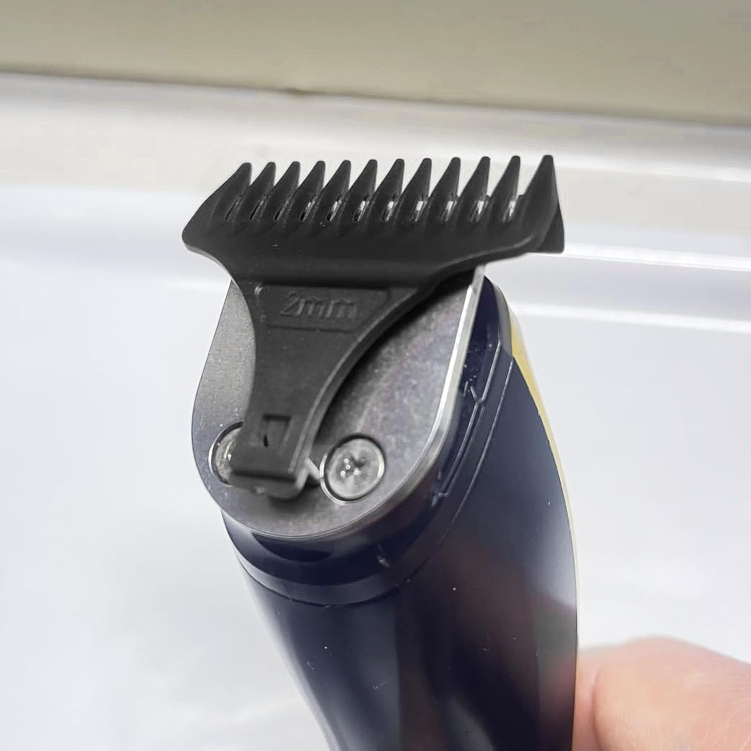 Nahaufnahme eines blauen Trimmers mit 2-mm-Aufsatz und silbernen Schrauben.