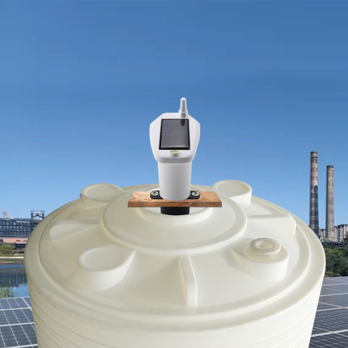 Weißer solarbetriebener Sensor auf einem Wassertank, im Hintergrund Schornsteine und Solarpaneele.