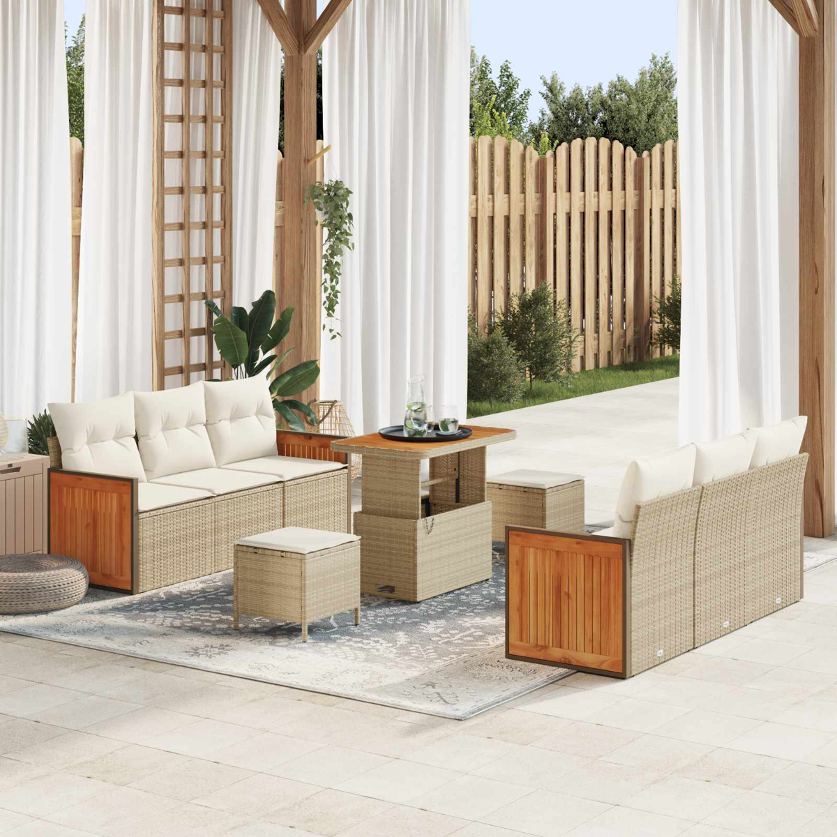 Ein Gartenmöbelset aus Rattan mit weißen Kissen, Tisch und Hockern auf einer Terrasse.