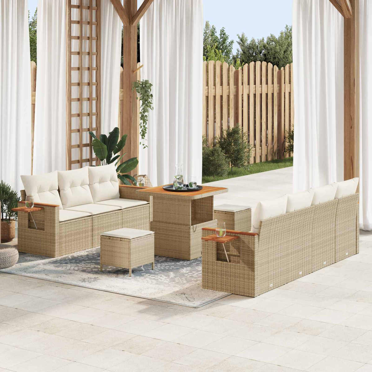 Geflochtene Outdoor-Möbel mit cremefarbenen Kissen, Holztisch und Holzzaun im Hintergrund.