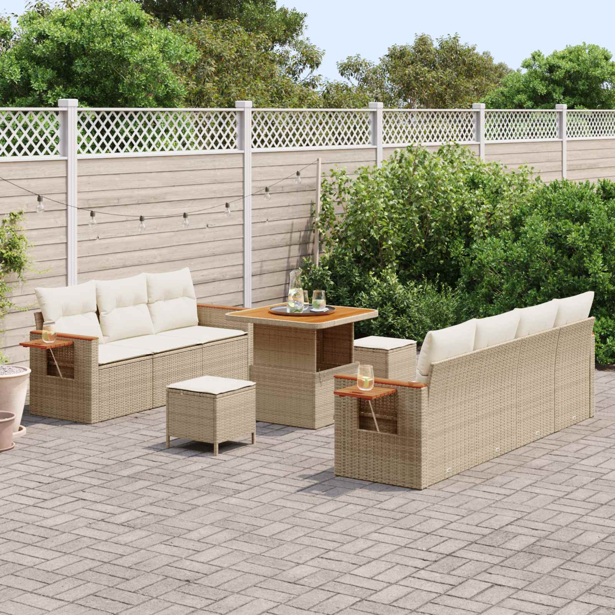 Eine Gartenlounge mit beigen Sitzkissen auf einem gepflasterten Hof mit Holzzaun.