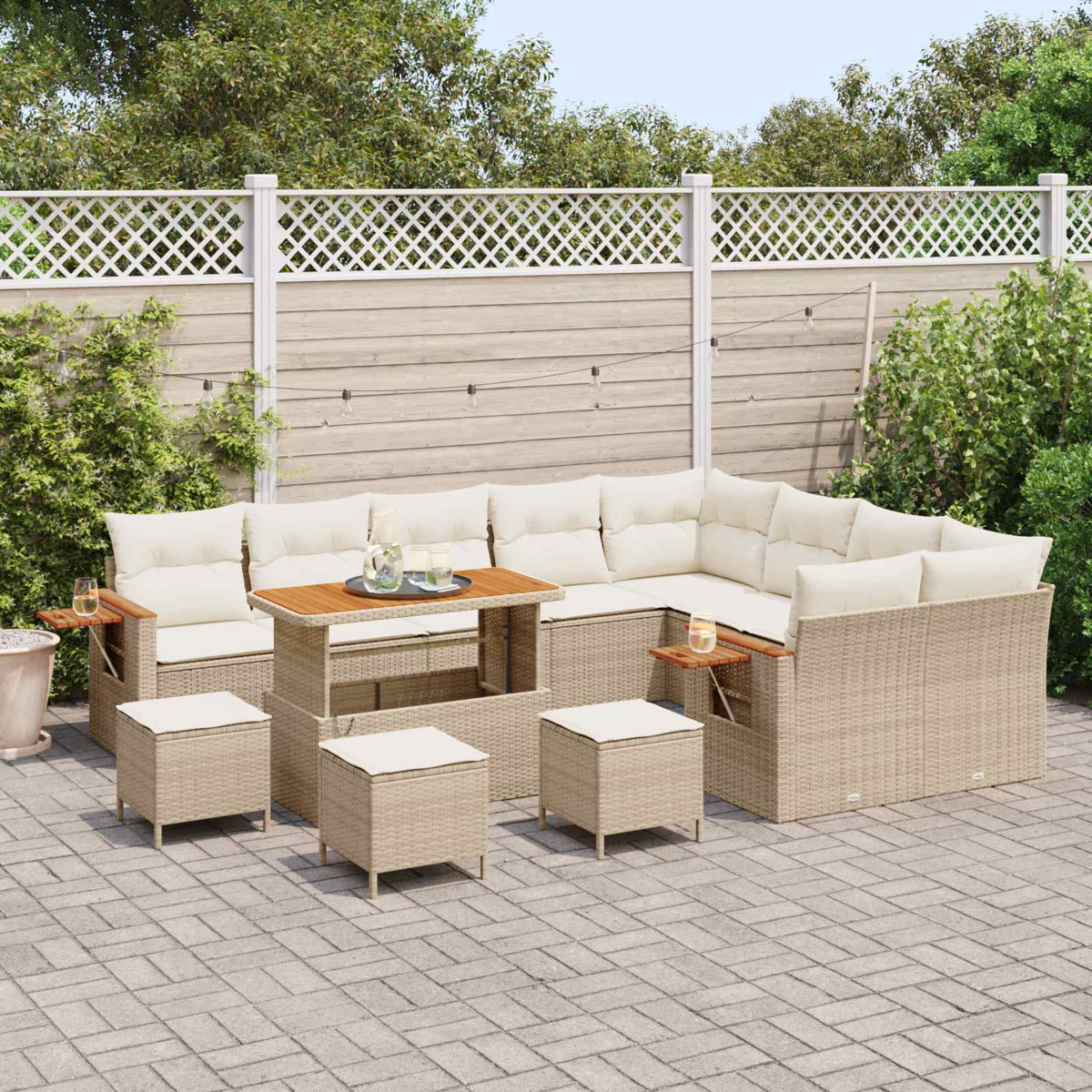 Ein beigefarbenes Lounge-Set aus Rattan mit cremefarbenen Kissen auf einer Kopfsteinpflasterterrasse.