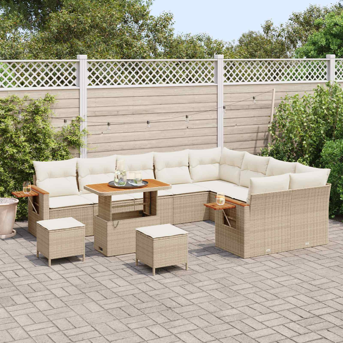 Ein beiger Rattansofa-Set mit hellen Kissen und Hocker auf einer gepflasterten Terrasse.