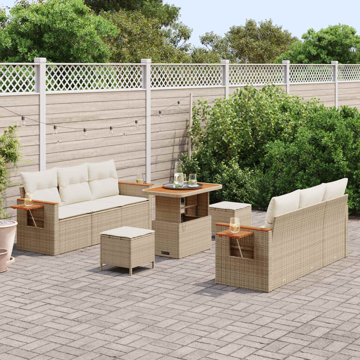Gartenmöbel aus Rattan mit cremefarbenen Kissen auf einer Steinterrasse.