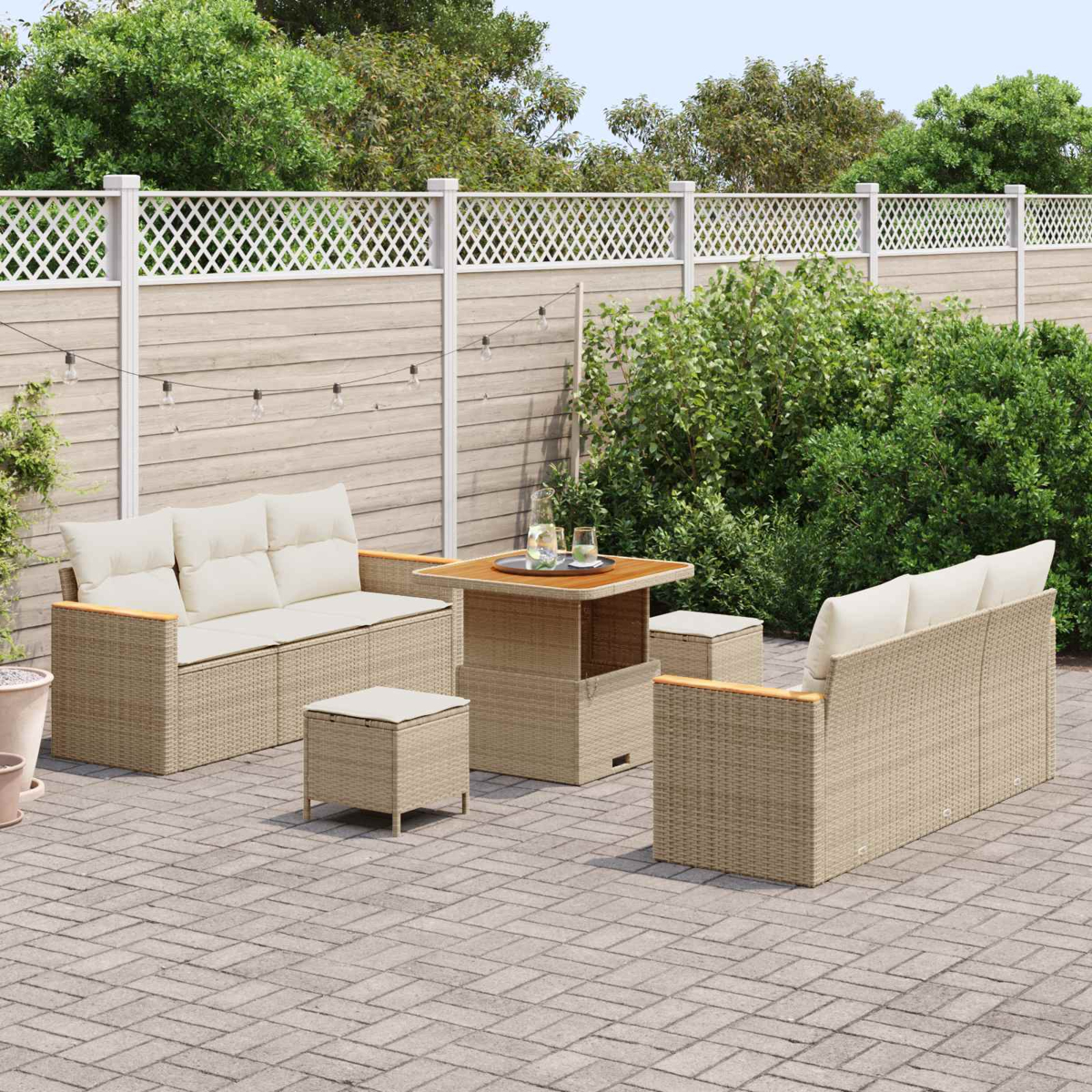 Ein beiger Rattansofa-Set mit Tisch und Hockern auf einer gepflasterten Terrasse.