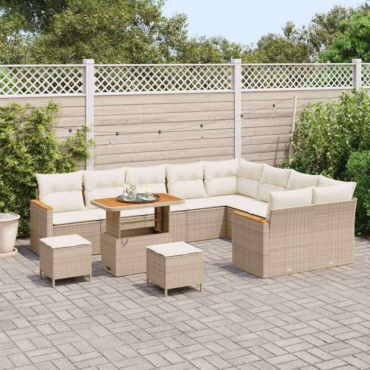 Ein beigefarbenes Lounge-Set mit Kissen und einem höhenverstellbaren Tisch auf einer gepflasterten Terrasse.