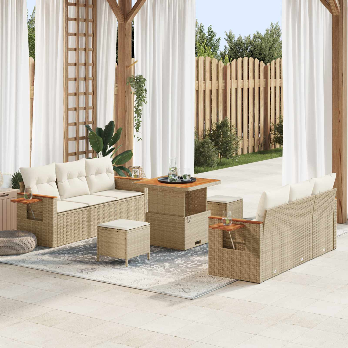 Ein beiger Rattansofa-Set mit Tisch und Hockern auf einer Terrasse unter weißen Vorhängen.