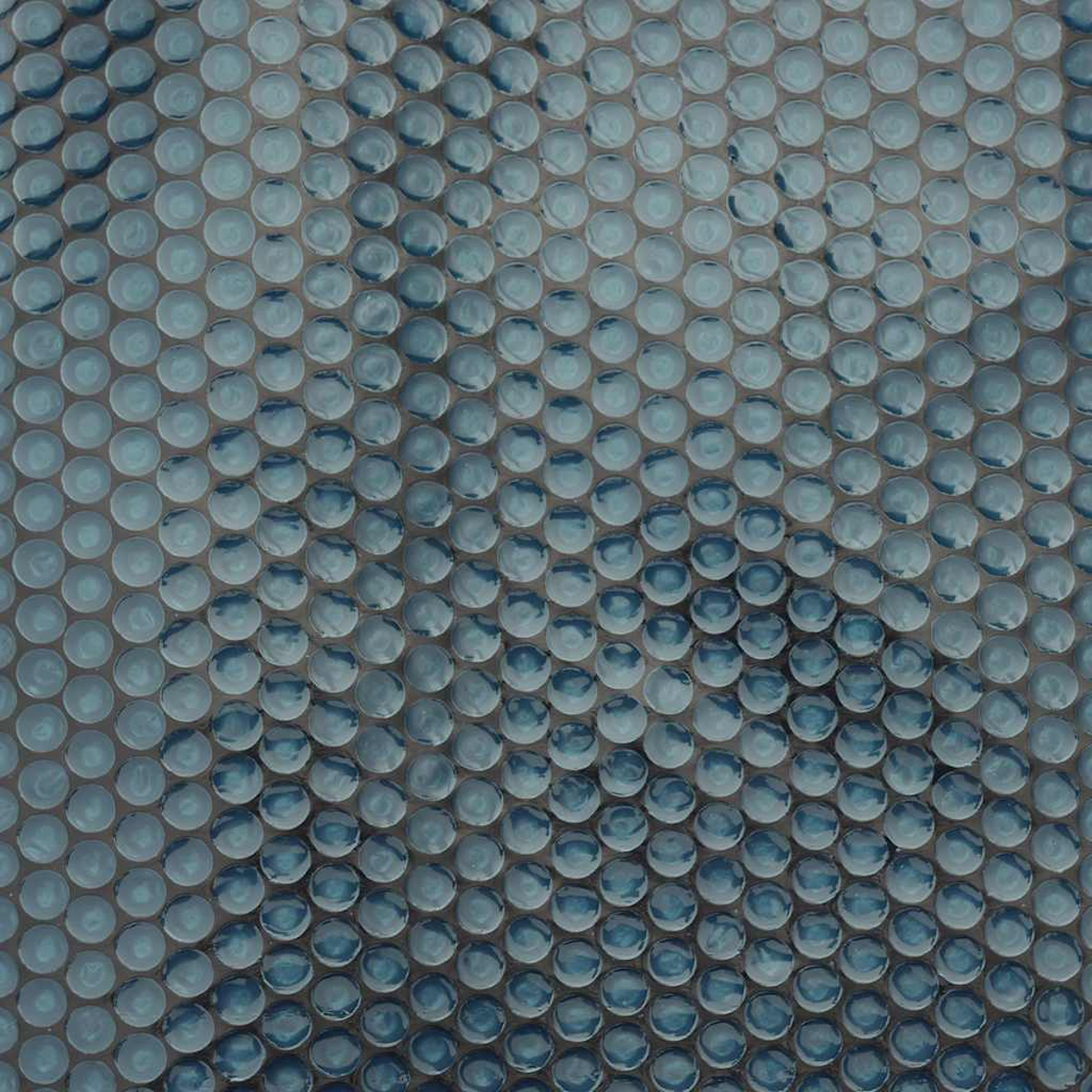 Nahaufnahme von blauen Mosaikfliesen mit kreisförmiger Textur. Die Fliesen sind hellblau mit dunkleren Schatten.