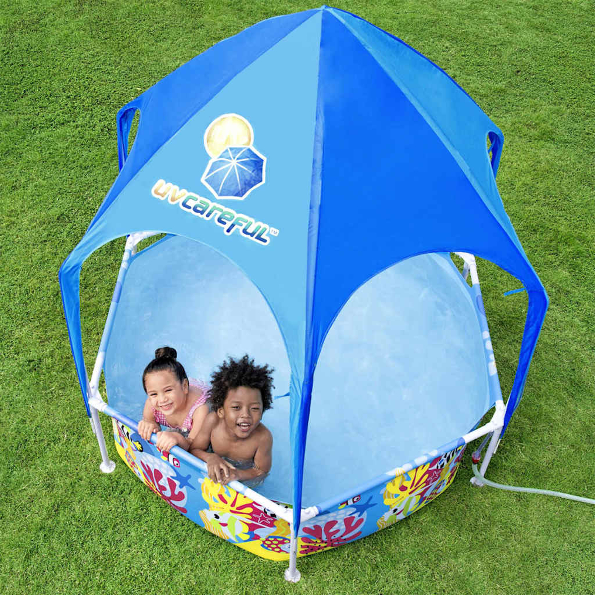 Due bambini sguazzano in una piscina blu con tettoia sull'erba.