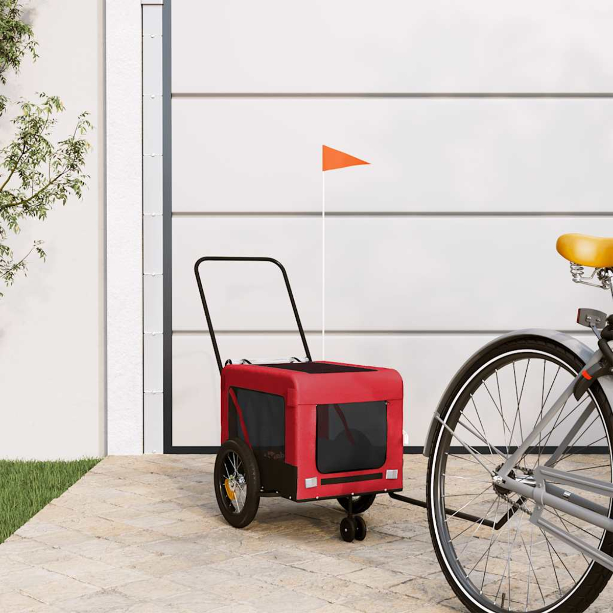 Ein roter Fahrradanhänger mit orangem Fähnchen steht neben einem Fahrrad.