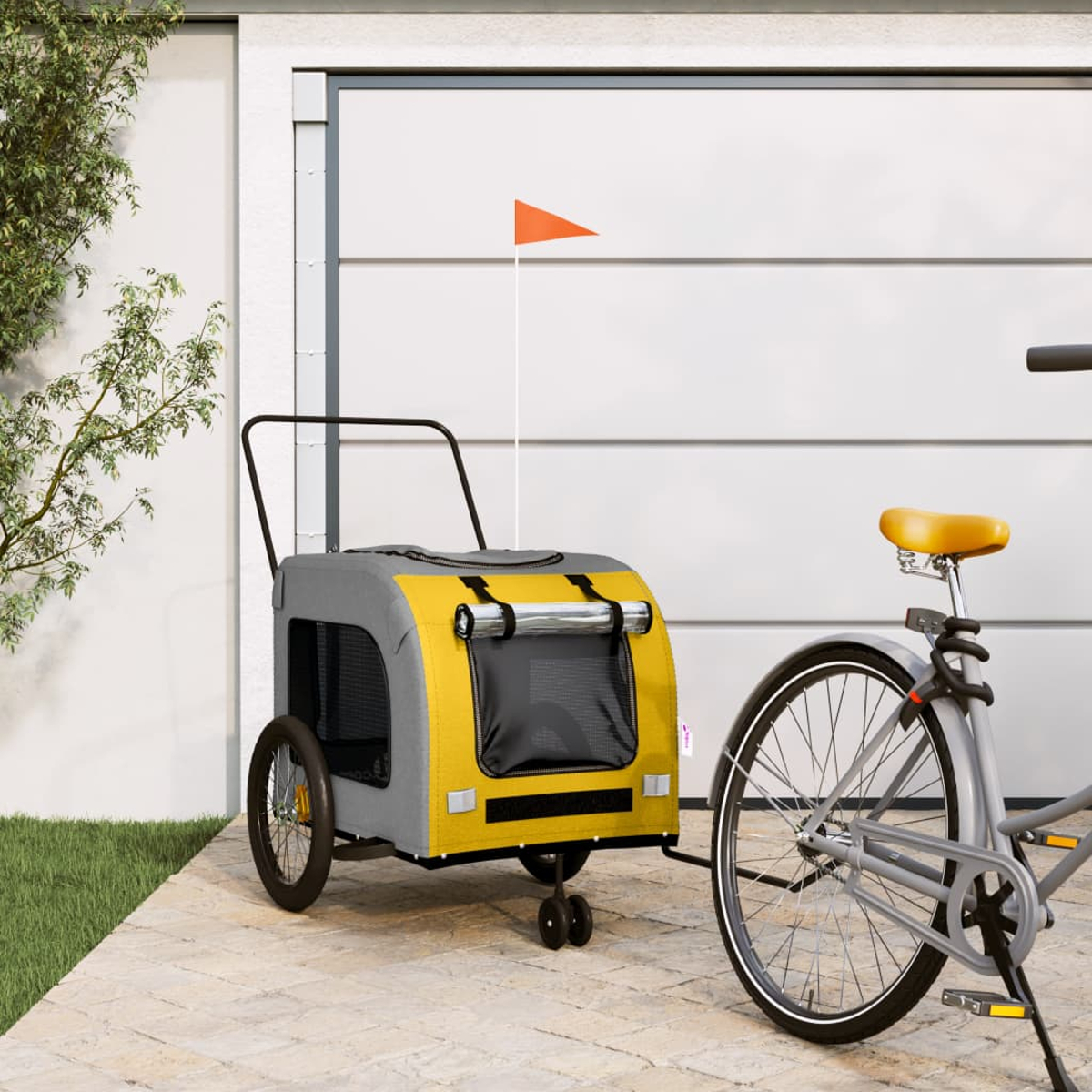 Ein grauer und gelber Fahrradanhänger mit orangefarbener Fahne steht neben einem Fahrrad.