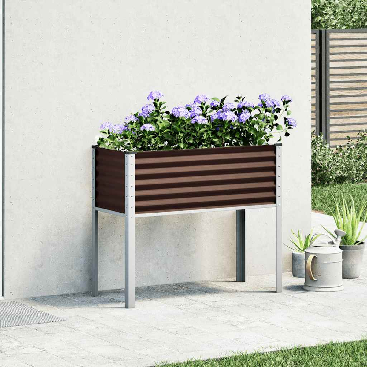 Un'aiuola rialzata con fiori viola si trova su un patio vicino a un muro.