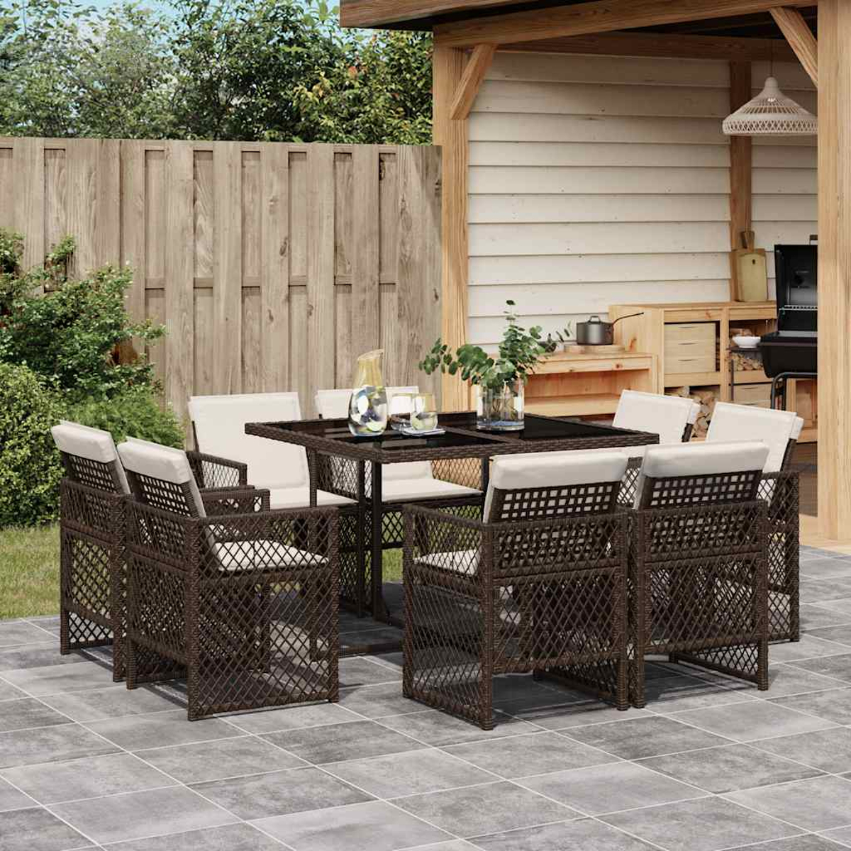 Geflochtene braune Gartenmöbel mit weißen Kissen unter einem Holzpavillon.