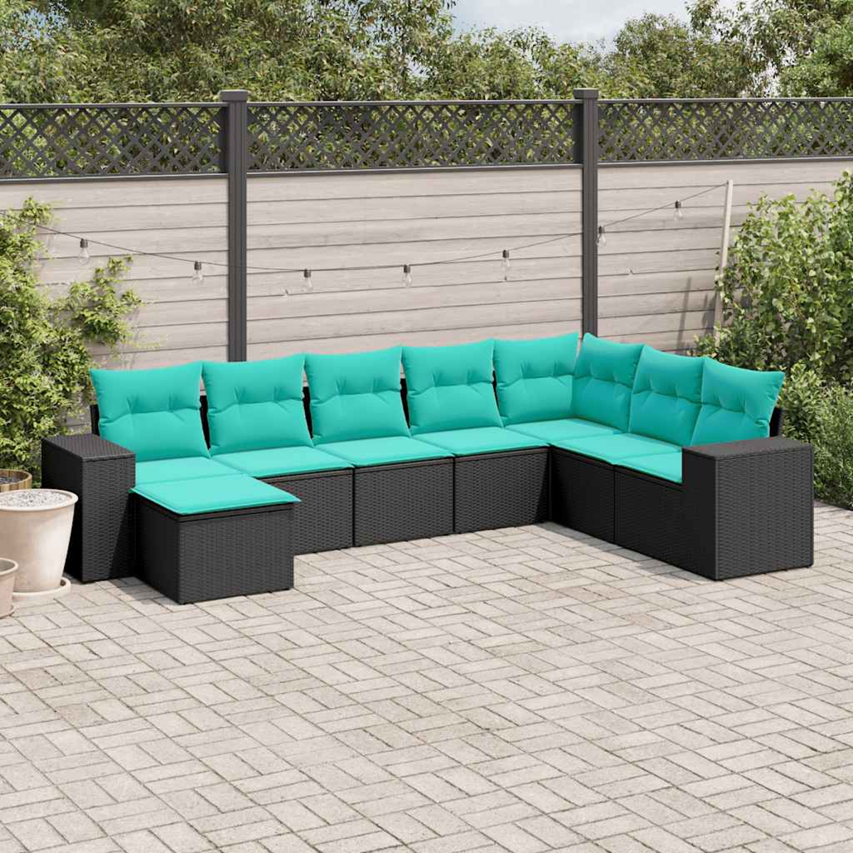Sofá esquinero gris oscuro con cojines turquesa en un patio pavimentado.