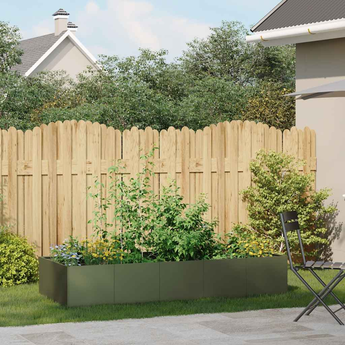 Una fioriera verde con piante si trova in un cortile con una recinzione di legno.