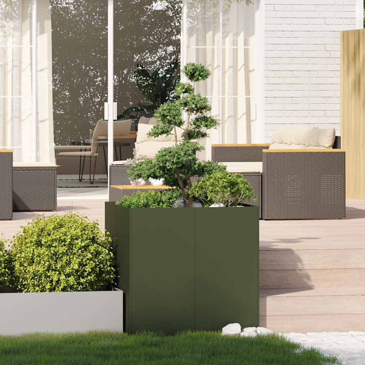 Un fioriera verde scuro con un bonsai e arbusti su una terrazza di legno.