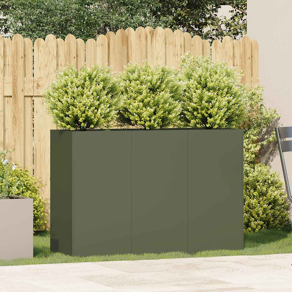 Un alto fioriera verde scuro con cespugli davanti, contro una recinzione di legno.