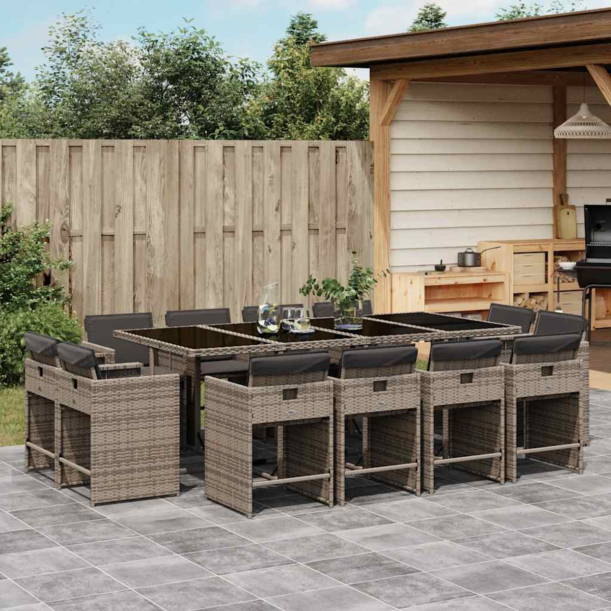 Ein Gartentisch und Hochstühle aus Rattan mit schwarzen Kissen unter einem Baldachin.