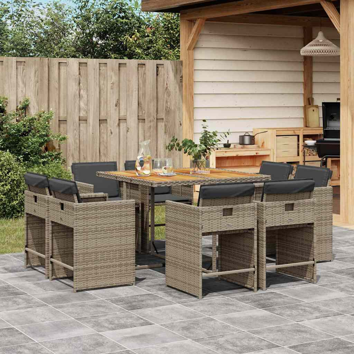 Gartensitzgruppe mit Hochtisch, Barhockern, Grill und Holzzaun.