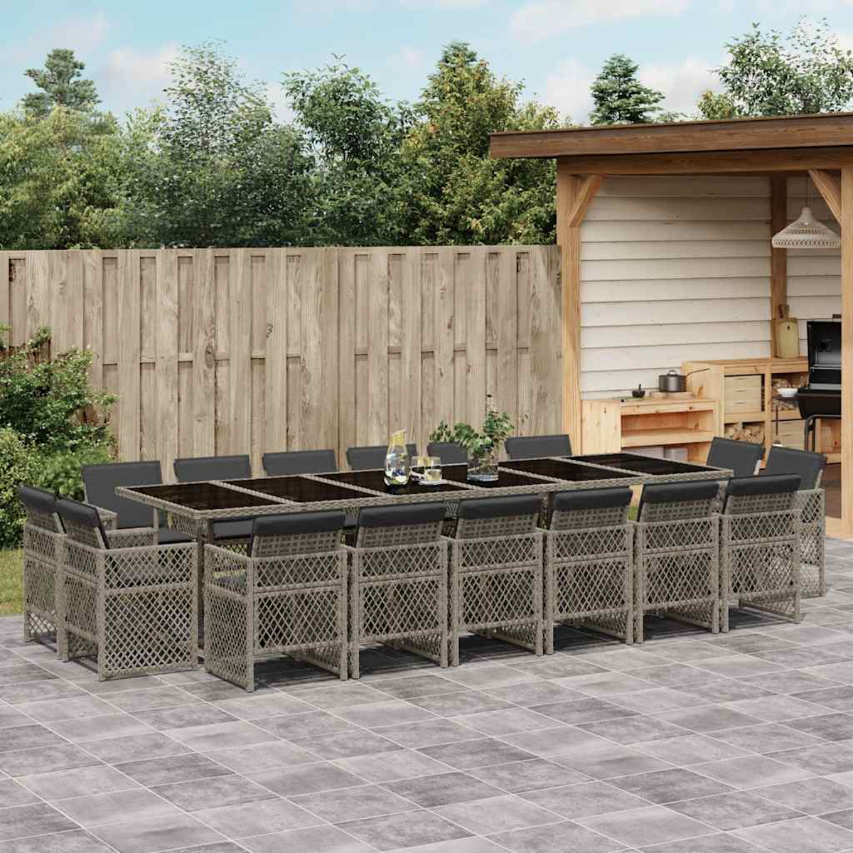 Ein langer Gartentisch mit 12 Stühlen, umgeben von einem Holzzaun und einem Unterstand.