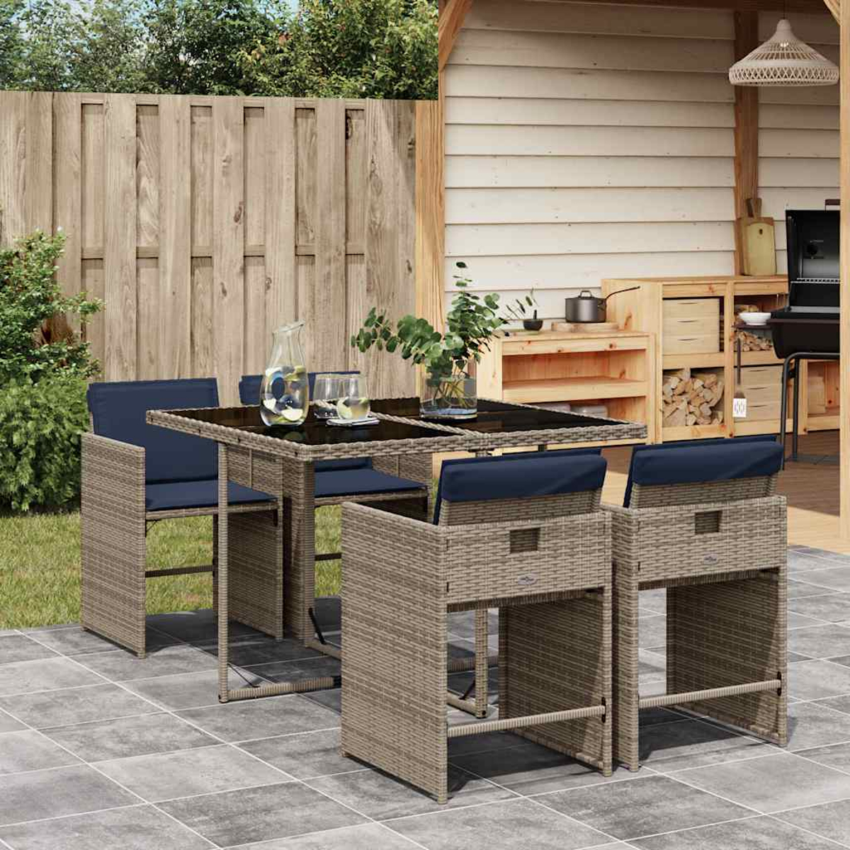 Ein Gartentisch und vier Stühle aus Rattan mit blauen Kissen stehen auf einer Terrasse.