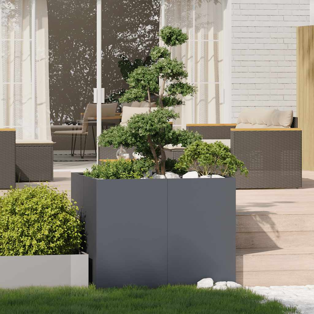 Un bonsai in un fioriera grigia su un ponte di legno con mobili all'esterno.