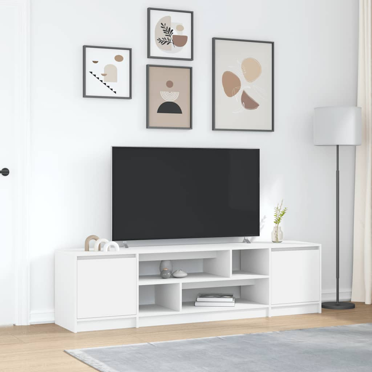 Ein moderner weißer TV-Schrank mit vier gerahmten Bildern an der Wand.