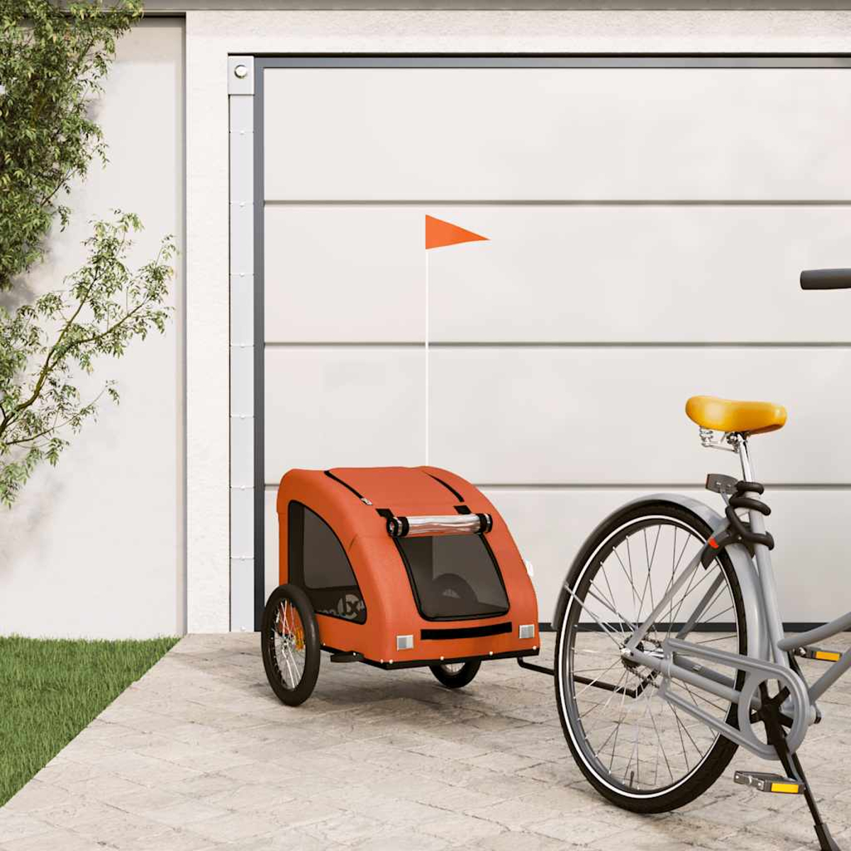 Orange Kinderfahrradanhänger mit Fahne neben einem grauen Fahrrad vor Garagentor.