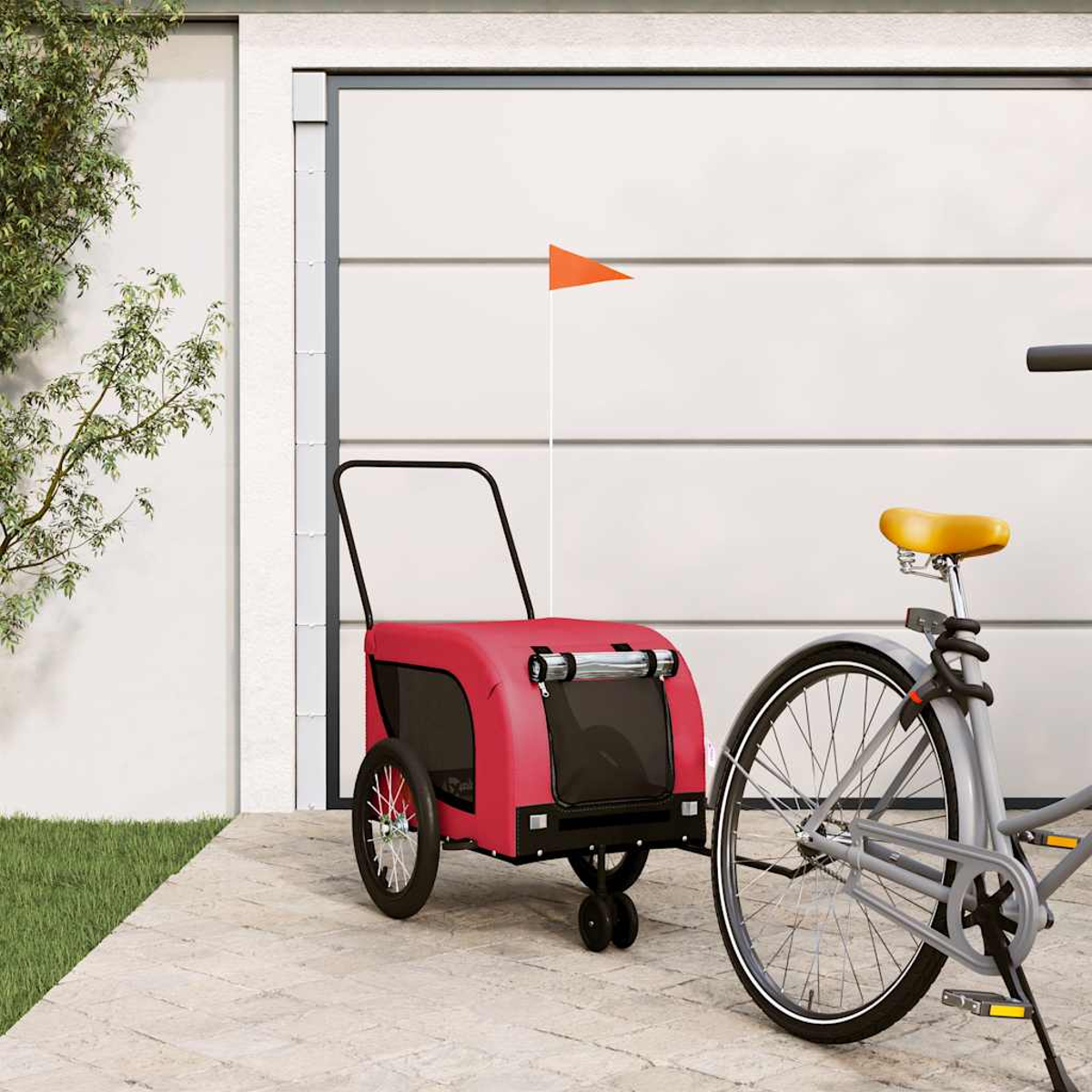 Ein roter Fahrradanhänger mit orangefarbener Flagge steht neben einem Fahrrad vor einem Garagentor.