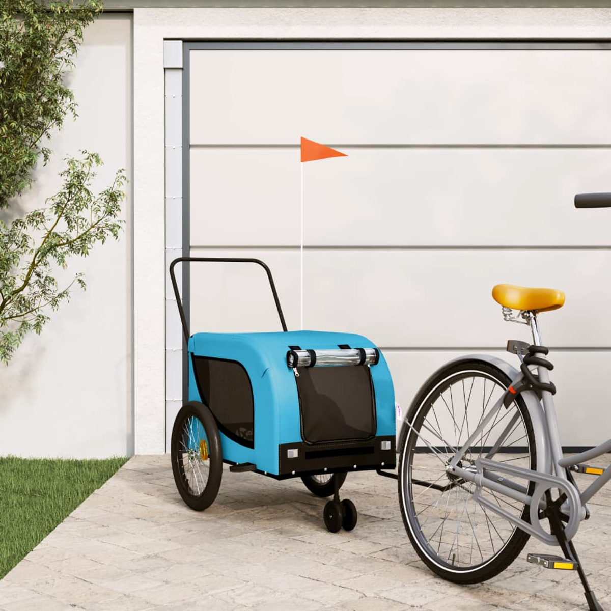 Ein blauer Fahrradanhänger mit orangefarbener Fahne steht neben einem Fahrrad vor einer Garage.