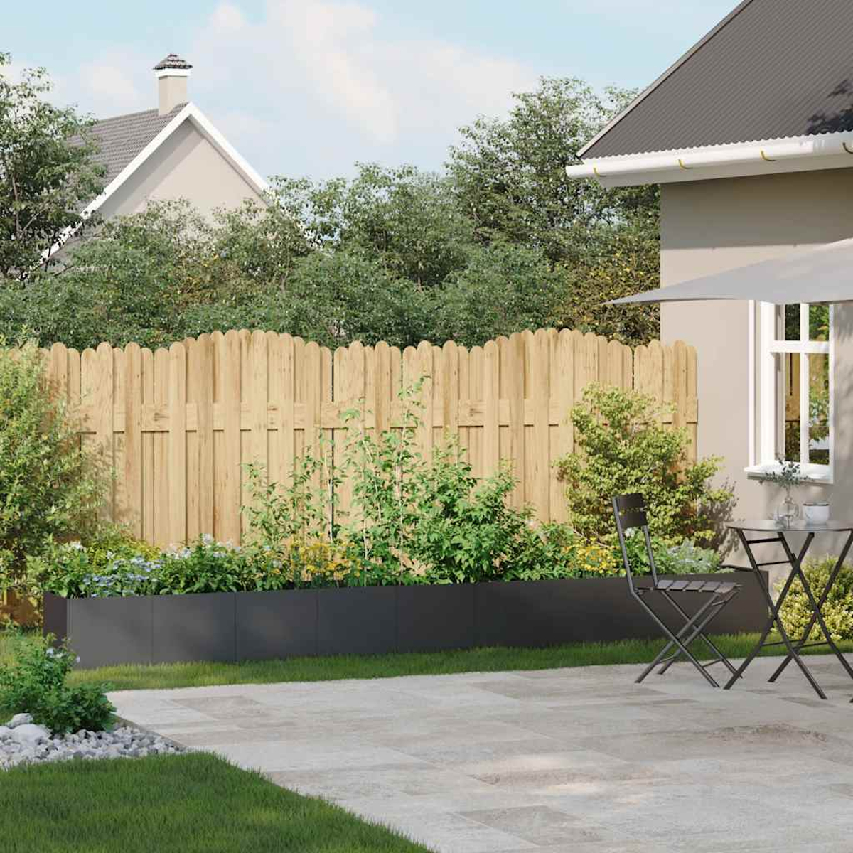 Una recinzione in legno delimita un giardino con fioriera rialzata, piante e tavolo con sedie.