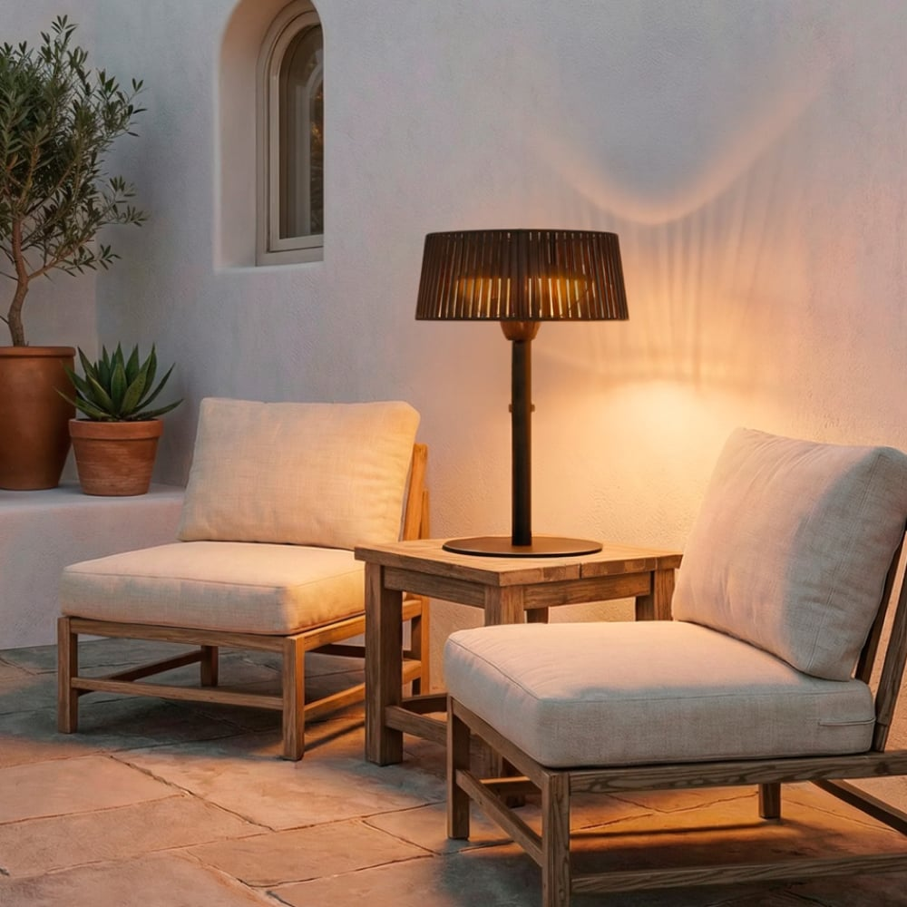 Dos sillones claros y una mesa con lámpara contra una pared blanca de noche.