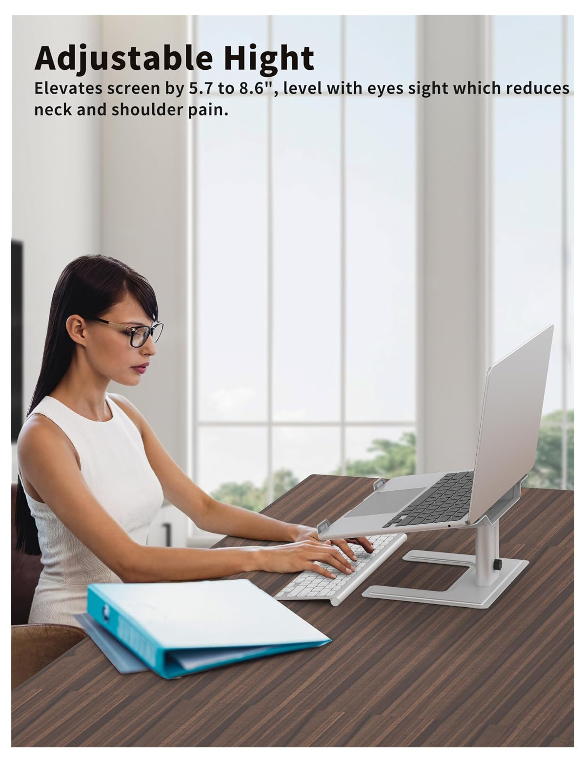 Frau am Schreibtisch mit Laptopständer, Tastatur und Ordnern.