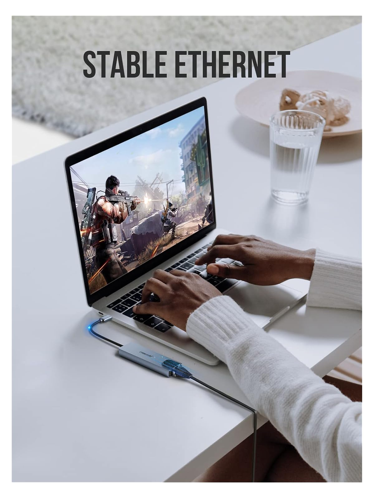 Person spielt Videospiel auf Laptop, verbunden mit Ethernet-Adapter. Text: STABLE ETHERNET.