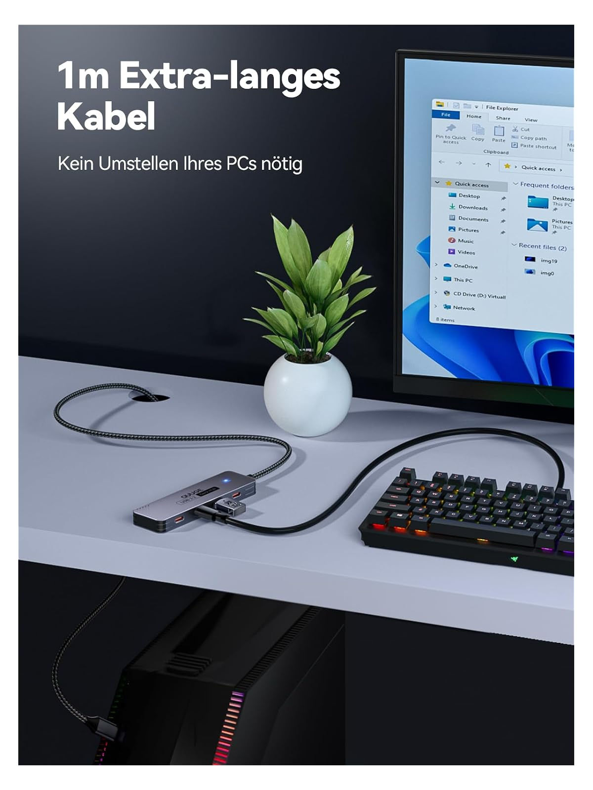 Ein silberner USB-Hub ist an ein schwarzes Kabel angeschlossen, neben einer Tastatur und einer Pflanze.