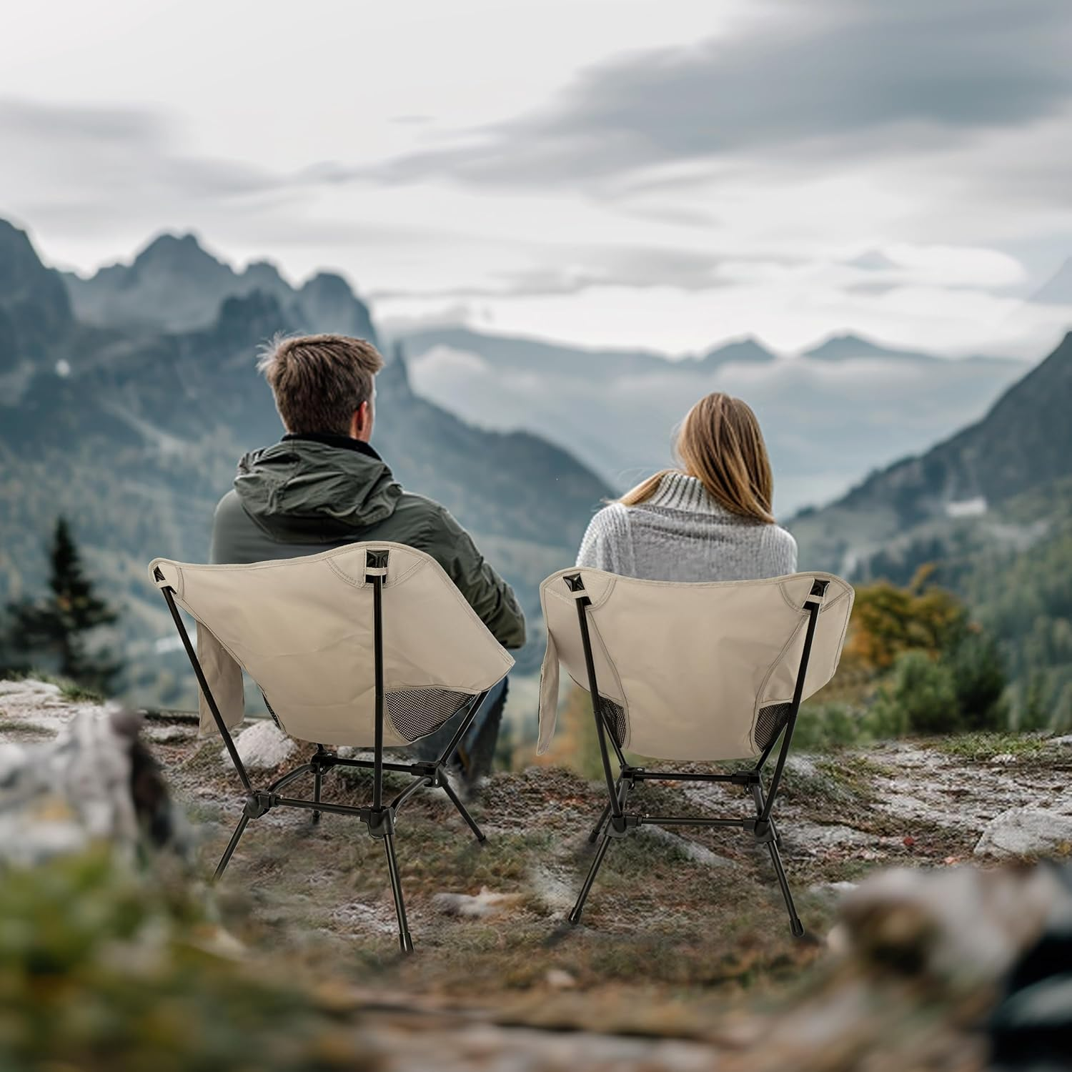 Mann und Frau sitzen auf Campingstühlen und blicken auf Berge.